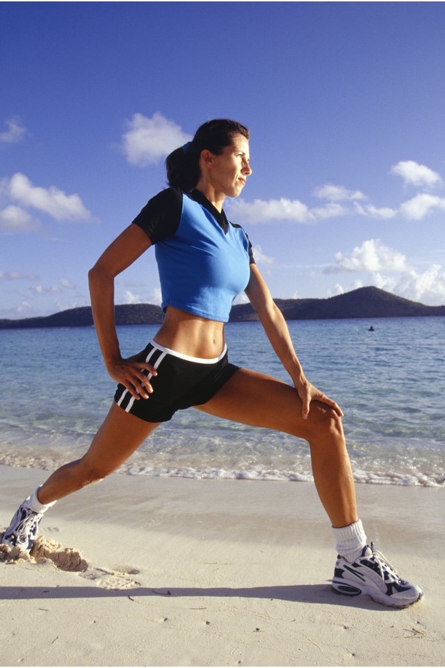 Woman performing stretching exercises on beach
