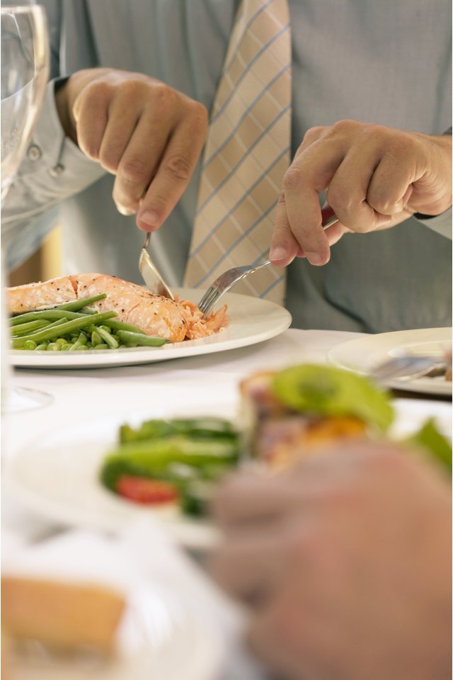 Businessman eating at restaurant table, mid section