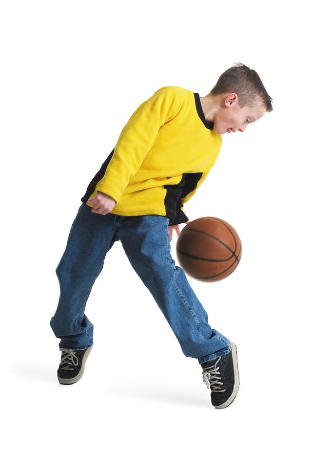 a young caucasian boy in a yellow shirt dribbles a basketball