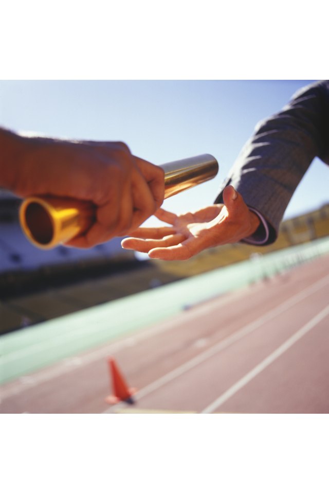 Two men passing golden baton in stadium, close-up