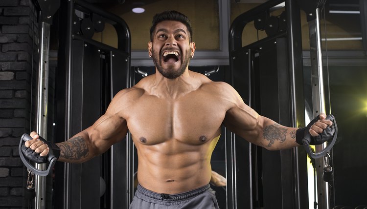 Muscular man doing cable fly exercise at the gym