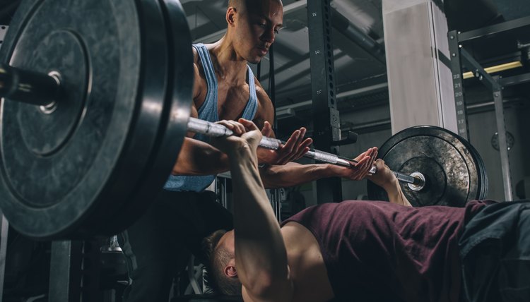 Two friends exercising bench press in gym
