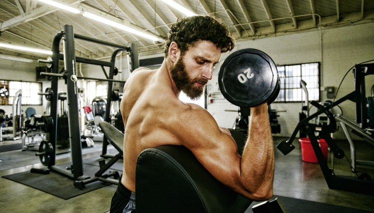 Mixed Race man lifting dumbbell in gymnasium