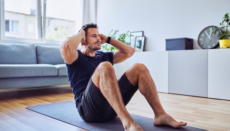Sporty man doing sit-ups exercise during home workout