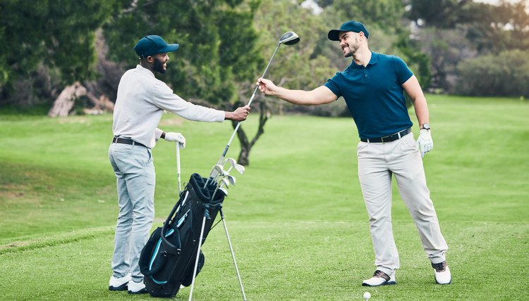 Golf, club and sports with men on course and playing for training, games and challenge. Tournament, help and support with golfer and caddy on lawn field for competition, hobby and leisure practice