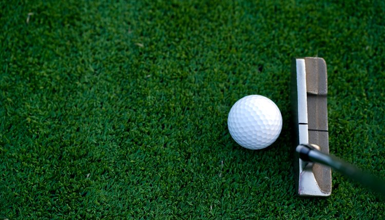 Golf clubs and golf balls on a green lawn in a beautiful golf course with morning sunshine.