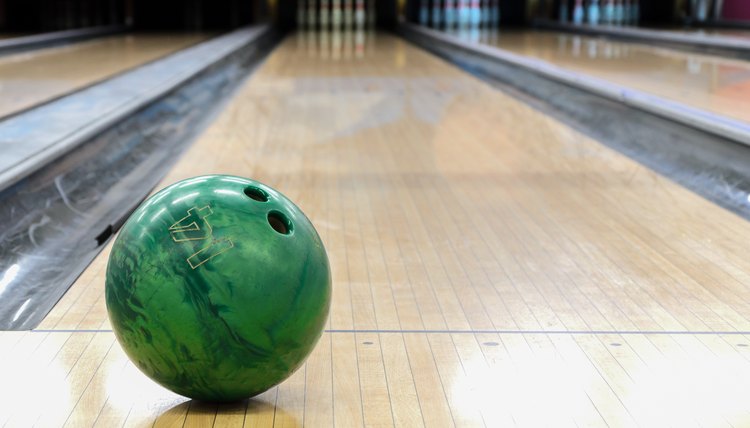 Close-up of green bowling ball against background of empty lanes in bowling alley