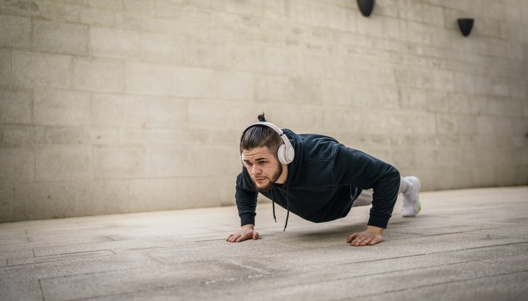 One man young adult caucasian male training outdoor doing push ups
