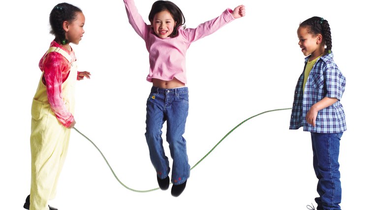 a group of three girls play jump rope together