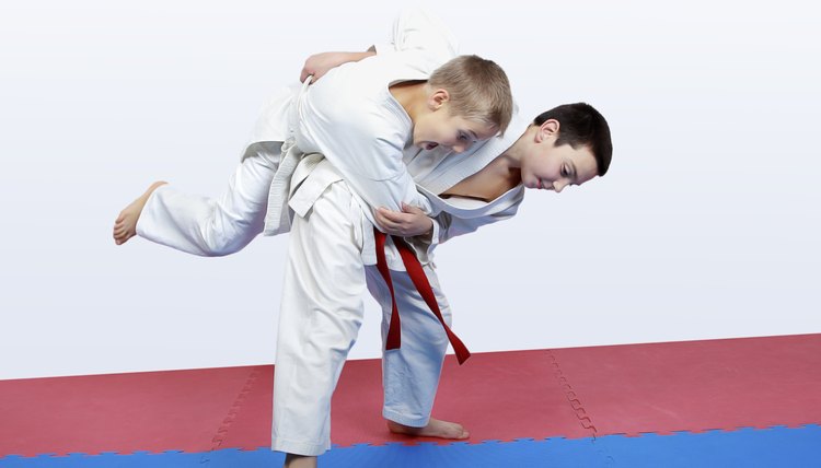 Boy athlete with a red sash makes hip throw