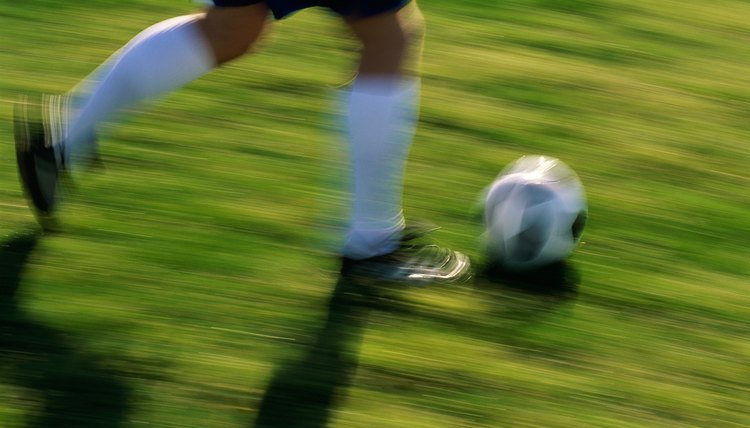 Low section view of a soccer player running with the ball