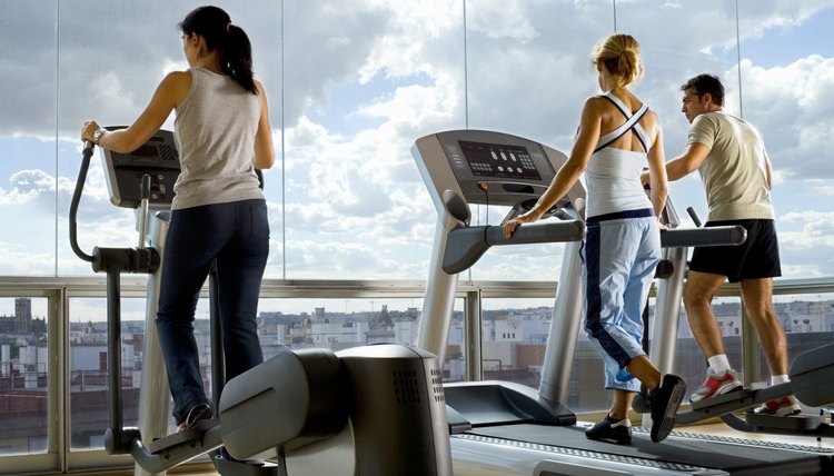 People using exercise equipment in front of a window