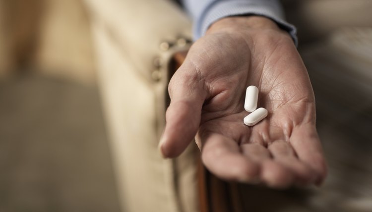 Senior woman holding two pills, close-up of hand