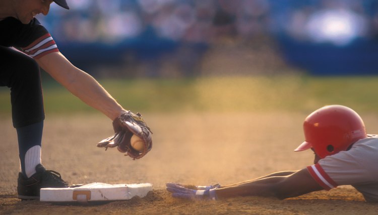Baseball player sliding into base as baseman tags him
