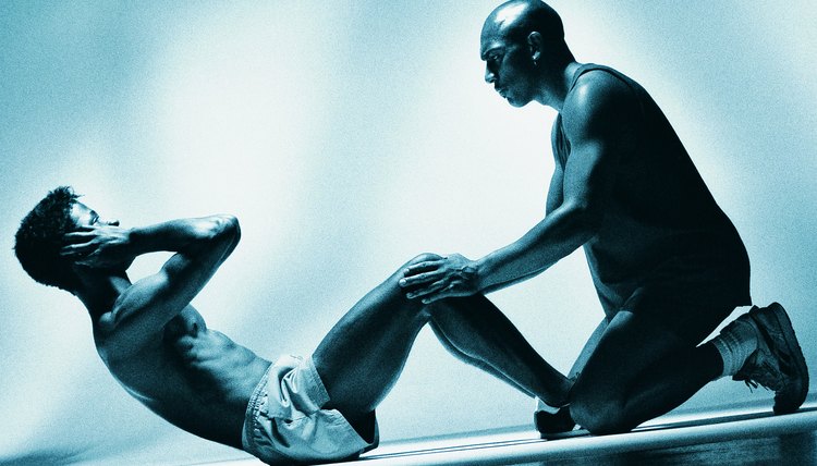 Man performing sit-ups with second man holding legs