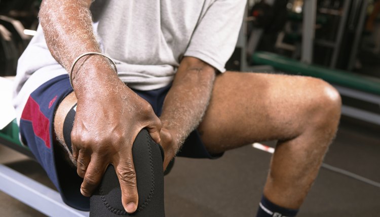 Senior man in gym wearing knee strap, holding knee, close-up
