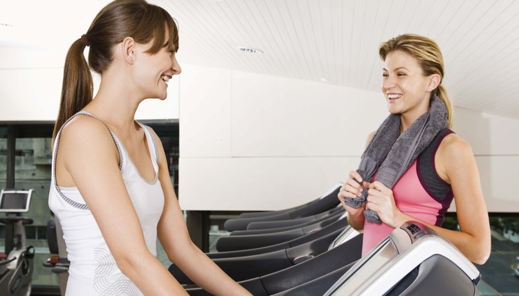 Woman on treadmill talking to woman at gym