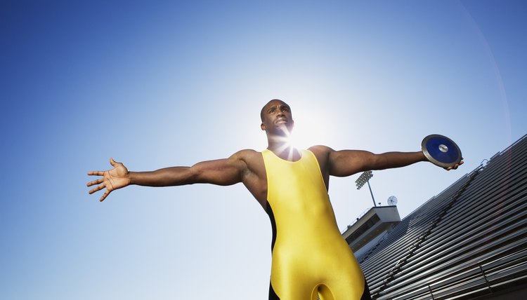 Man standing on athletic track holding a discus