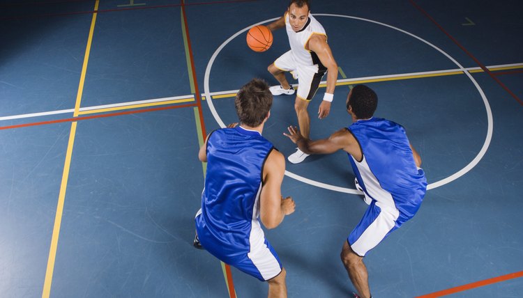 Man dribbling basketball against defenders