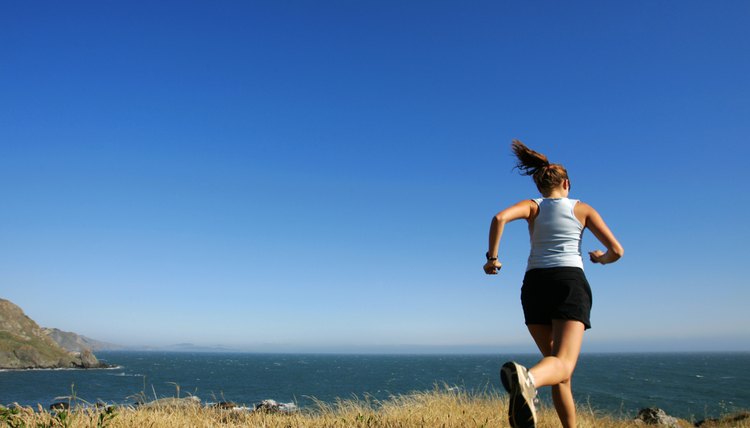 Woman running along coastline, California, USA