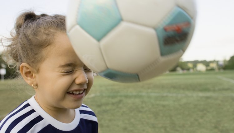 Young girl bouncing soccer ball off head