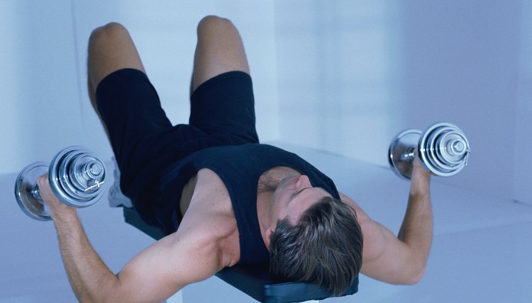 Man lying on bench  using dumbbells