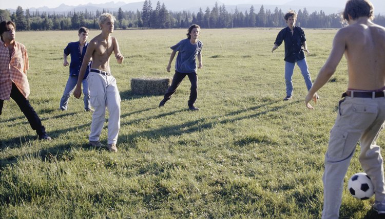Young men playing football, mountain scenery in background