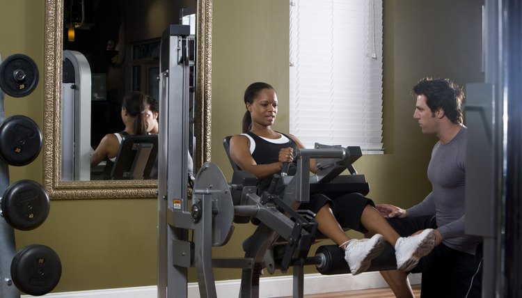 Trainer instructing a young woman with sports equipment in the gym