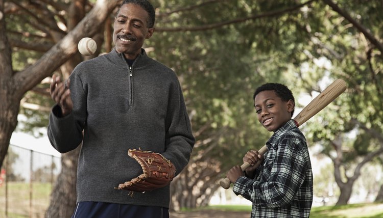 African man and son with baseball bat and glove in park