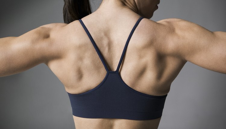 fitness portrait of a muscular female in a black workout outfit as she flexes her muscles
