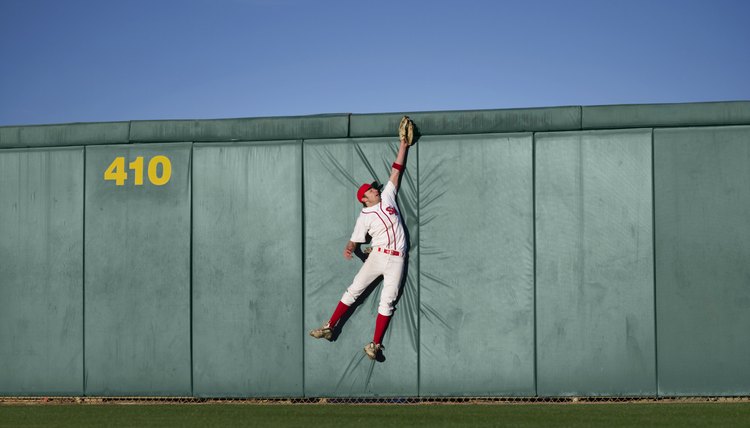 USA, California, San Bernardino, baseball player making leaping catch at wall