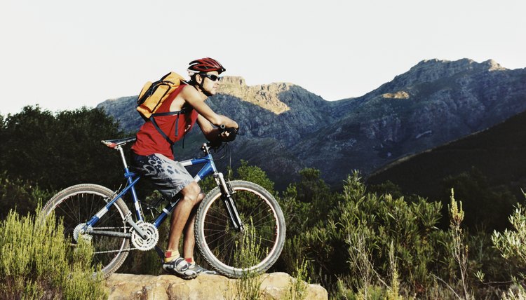 Young Man Sitting on a Bike and Looking at a View of Mountains