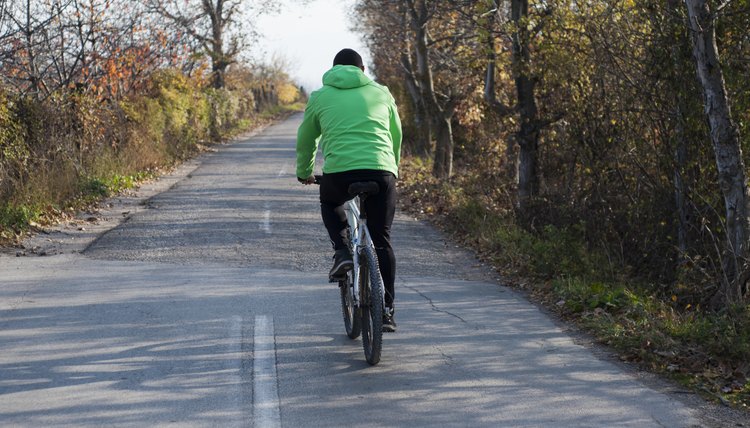 Rear View Of Young Man Enjoying Cycle Ride In Countryside