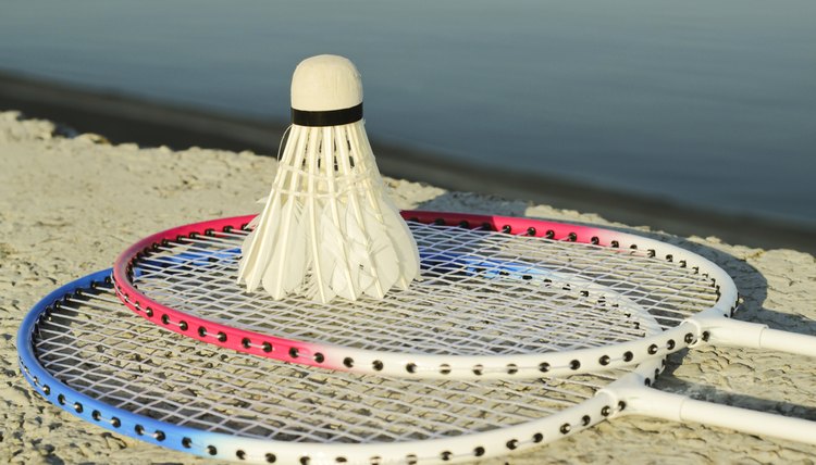 Badminton racquets with shuttlecock on a stone bench against the