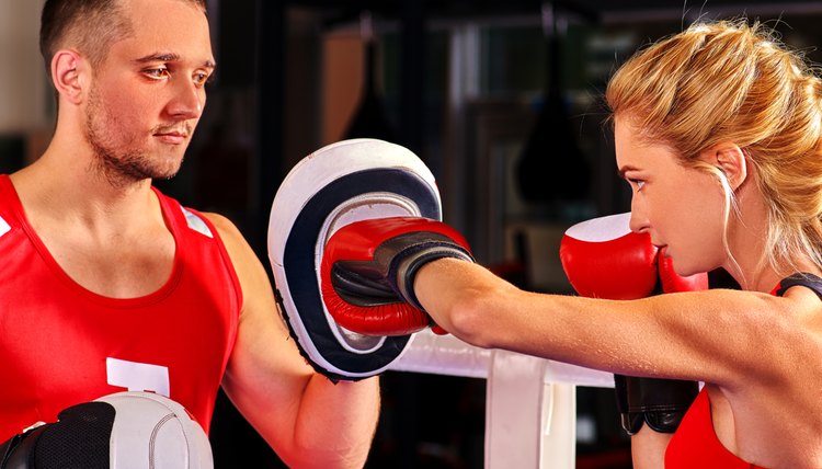 Female boxer throwing right cross at mitts