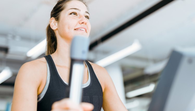 Beautiful young lady using the elliptical trainer