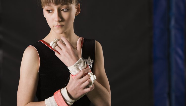 Pensive gymnast girl holding wrist