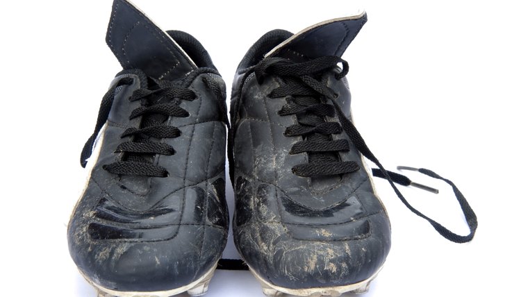 Dirty black leather football soccer boots on white