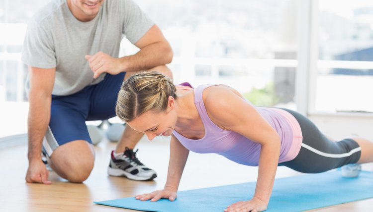Trainer assisting woman with push ups