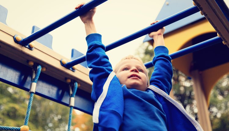little boy playing on monkey bars in autumn