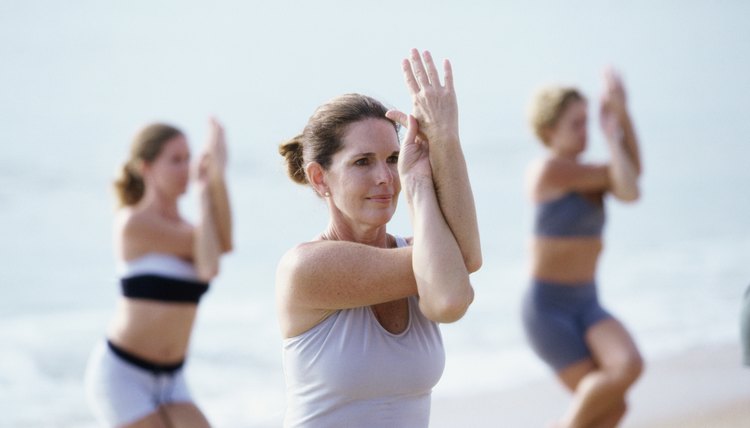 Group of people performing yoga on the beach