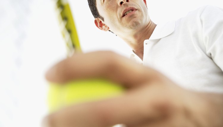 Low angle view of a man playing tennis holding tennis racket and tennis ball
