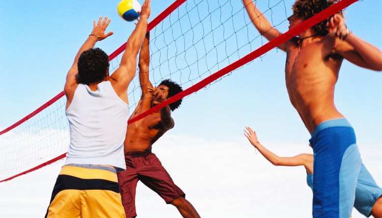 a group of people playing volleyball on the beach