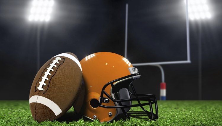 Football Ball and Helmet On Grass under Spotlights