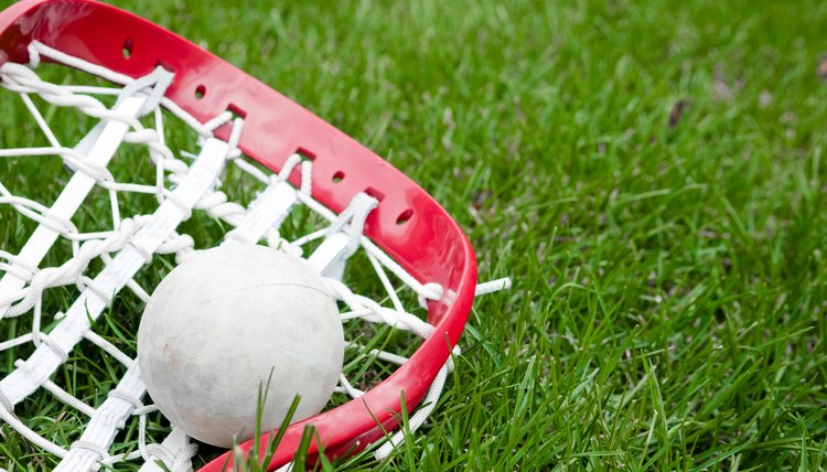 Girls lacrosse head and grey ball on grass