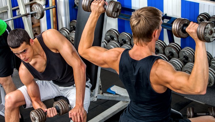 Group of men working with dumbbells at gym